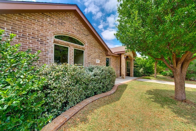 exterior space featuring brick siding and a yard