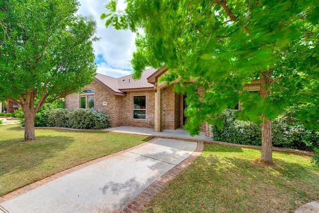 view of front of property with a front yard, a patio area, and brick siding