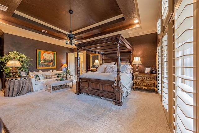 carpeted bedroom with a raised ceiling and ornamental molding