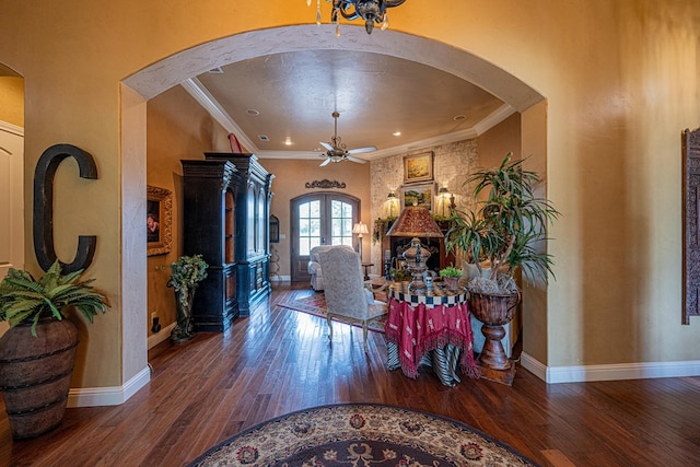 foyer with arched walkways, ceiling fan, wood-type flooring, crown molding, and baseboards