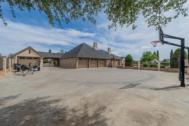 view of side of property featuring fence, concrete driveway, and a chimney