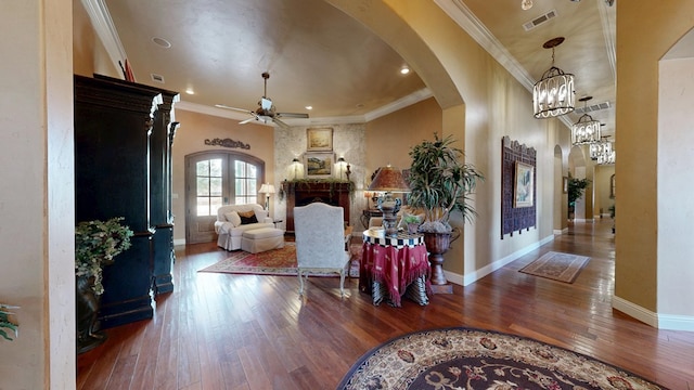 foyer with arched walkways, ceiling fan, wood-type flooring, a fireplace, and baseboards
