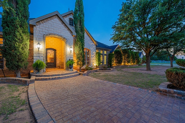 french country style house with stone siding and brick siding
