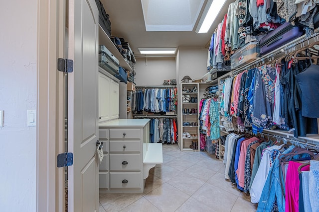 walk in closet with attic access and light tile patterned floors