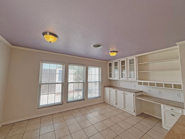 3619 W Wadley Ave, Midland, TX 79707 - kitchen with open shelves, built in desk, white cabinets, light tile patterned flooring, and a textured ceiling
