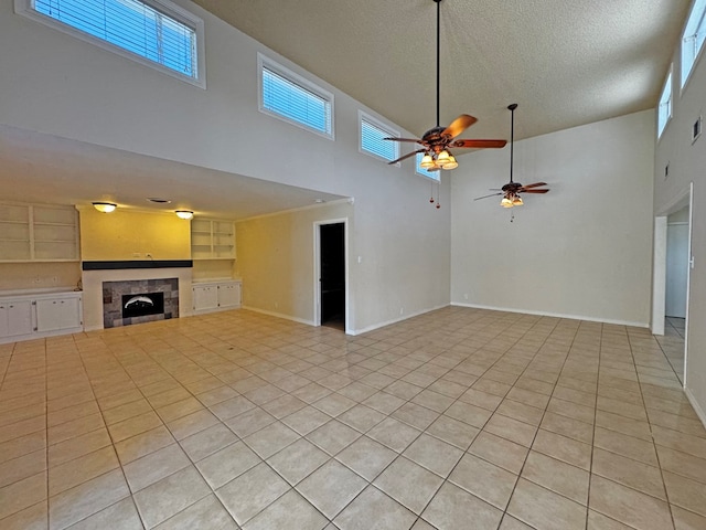 3619 W Wadley Ave, Midland, TX 79707 - unfurnished living room with a high ceiling, ceiling fan, a textured ceiling, built in shelves, and light tile patterned floors