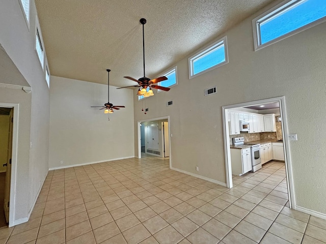 3619 W Wadley Ave, Midland, TX 79707 - unfurnished living room with light tile patterned floors, a textured ceiling, a ceiling fan, and a high ceiling