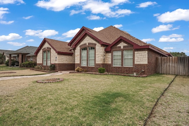 4626 Crockett Ave, Midland, TX 79703 - view of front of house featuring stone siding, a shingled roof, a front yard, fence, and brick siding