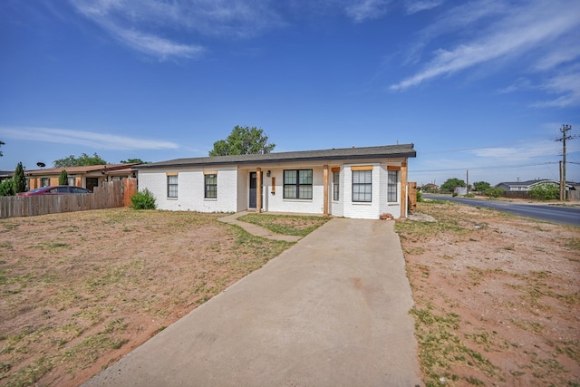 view of front of house featuring fence, driveway, and brick siding