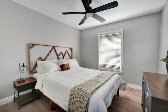 bedroom featuring baseboards, wood finished floors, and ceiling fan