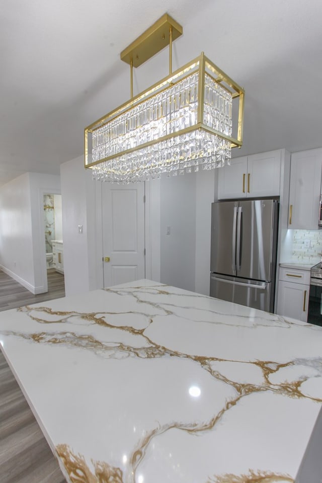 2702 Ann Dr, Big Spring, TX 79720 - kitchen with light wood-style floors, stainless steel appliances, light stone counters, white cabinets, and decorative backsplash