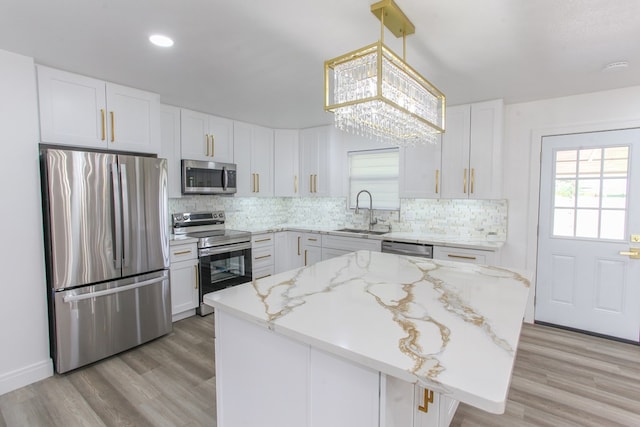2702 Ann Dr, Big Spring, TX 79720 - kitchen featuring appliances with stainless steel finishes, decorative backsplash, white cabinets, light stone countertops, and light wood-style floors