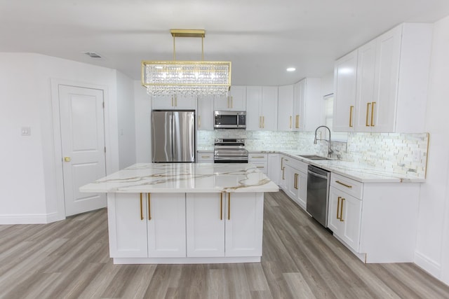 2702 Ann Dr, Big Spring, TX 79720 - kitchen with appliances with stainless steel finishes, light wood-style floors, tasteful backsplash, light stone countertops, and white cabinets
