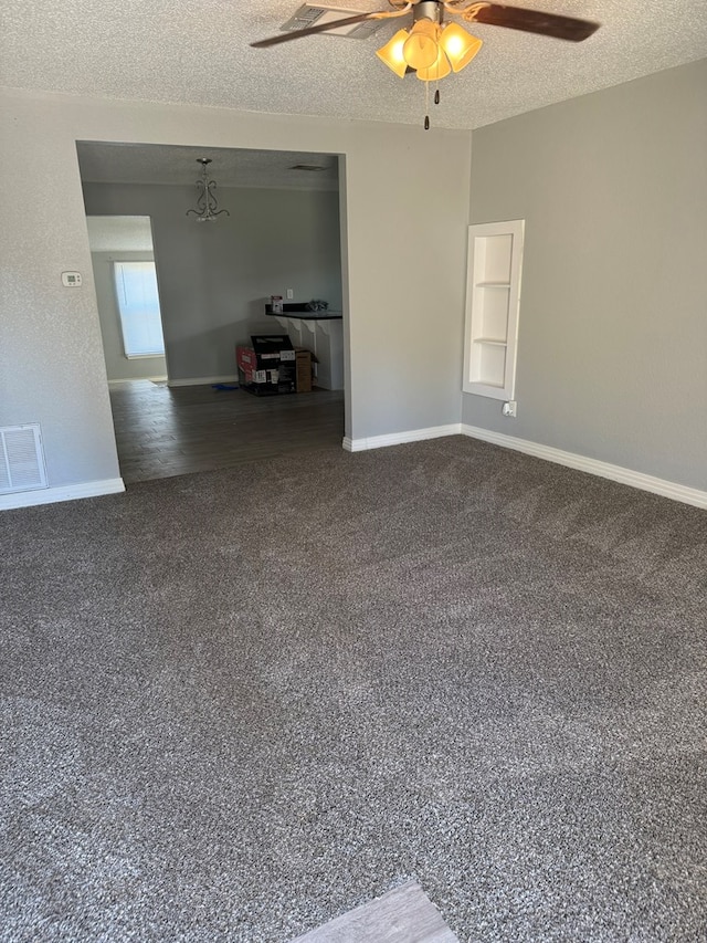 empty room with ceiling fan, dark colored carpet, a textured ceiling, and visible vents