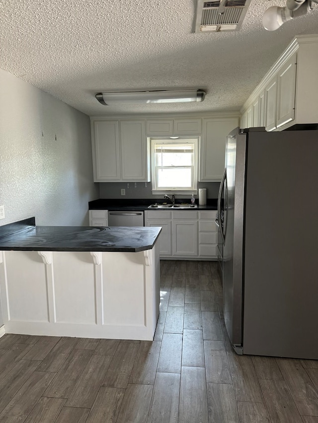 kitchen with dark countertops, stainless steel appliances, dark wood finished floors, and a textured ceiling