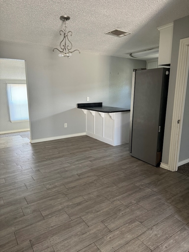 spare room featuring baseboards, dark wood-style flooring, and a textured ceiling