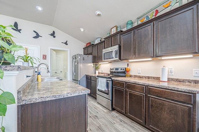 kitchen featuring sink, appliances with stainless steel finishes, dark brown cabinetry, an island with sink, and vaulted ceiling