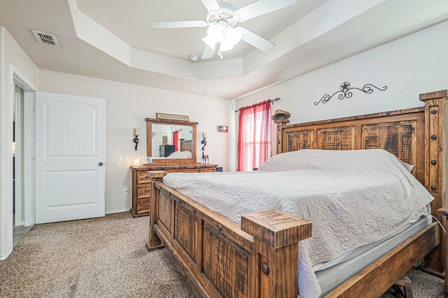 carpeted bedroom featuring ceiling fan and a tray ceiling