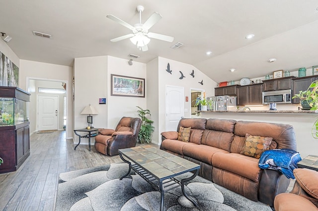 living room featuring vaulted ceiling, light hardwood / wood-style floors, and ceiling fan