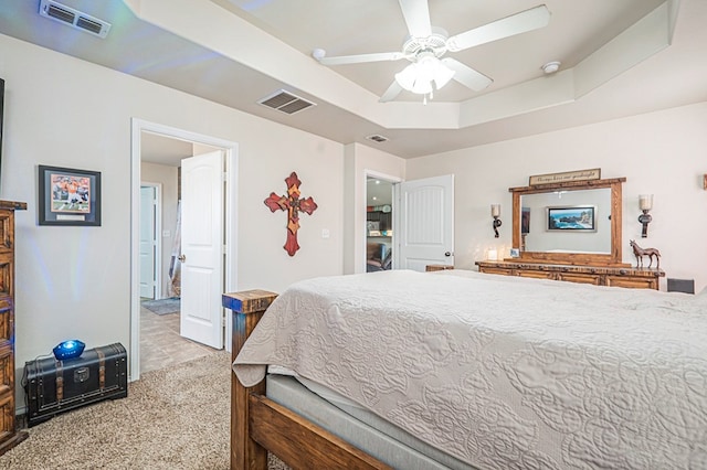 carpeted bedroom with a raised ceiling and ceiling fan