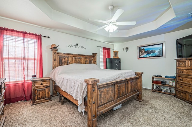 bedroom with light carpet, ceiling fan, and a tray ceiling