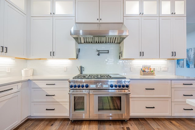 kitchen featuring wood finished floors, exhaust hood, white cabinetry, light countertops, and double oven range