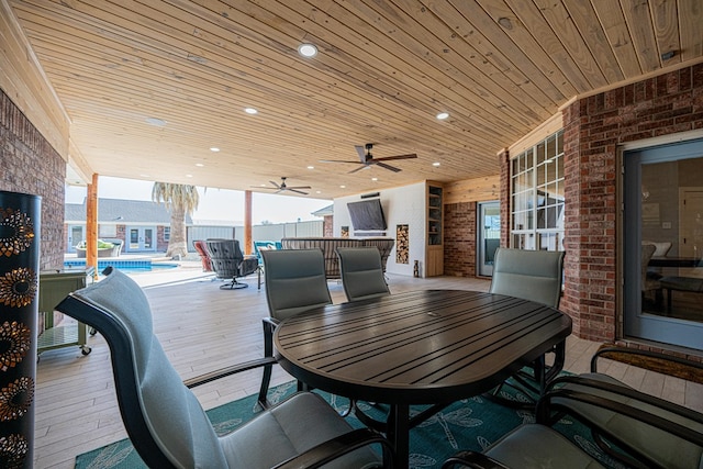 view of patio / terrace with ceiling fan, outdoor dining area, a wooden deck, and a fenced in pool