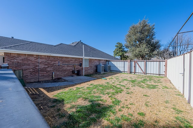 view of yard featuring a gate, a fenced backyard, and central AC unit