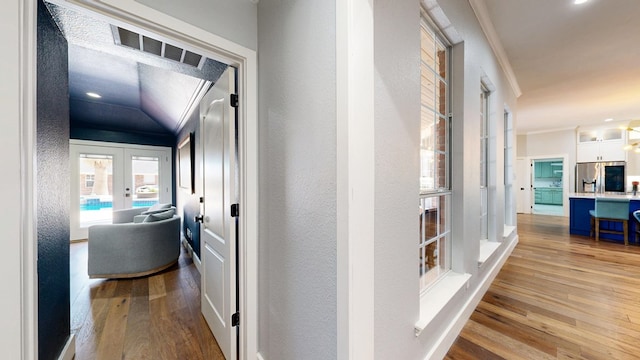 hall featuring a textured wall, visible vents, french doors, light wood-type flooring, and crown molding