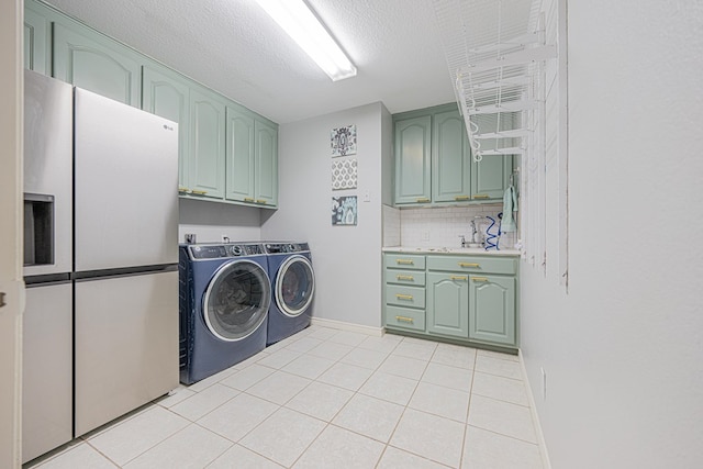 laundry room with light tile patterned floors, cabinet space, a textured ceiling, independent washer and dryer, and baseboards