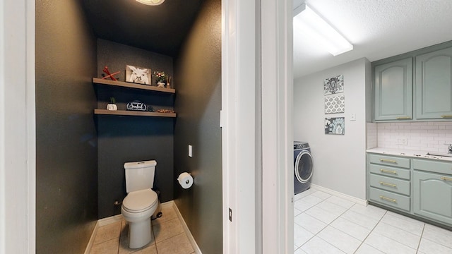 bathroom with toilet, washer / clothes dryer, vanity, tile patterned floors, and tasteful backsplash