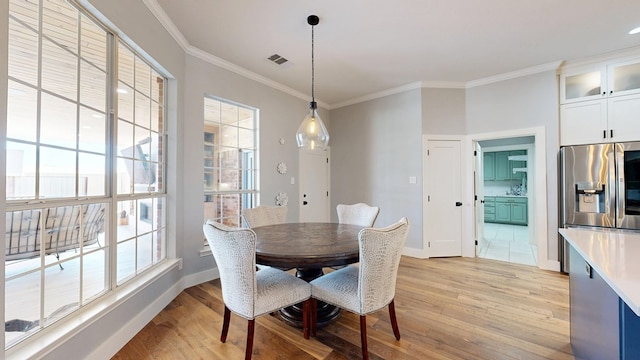 dining area with light wood-type flooring, visible vents, crown molding, and baseboards