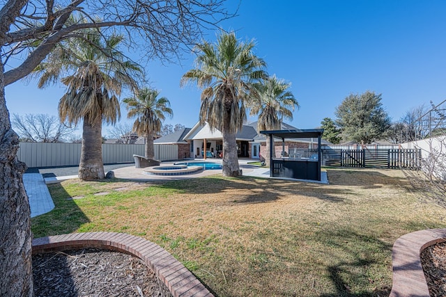 view of yard with a patio area, a fenced backyard, and a pool with connected hot tub