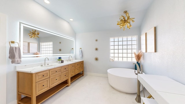 bathroom with vaulted ceiling, a sink, a freestanding bath, and double vanity