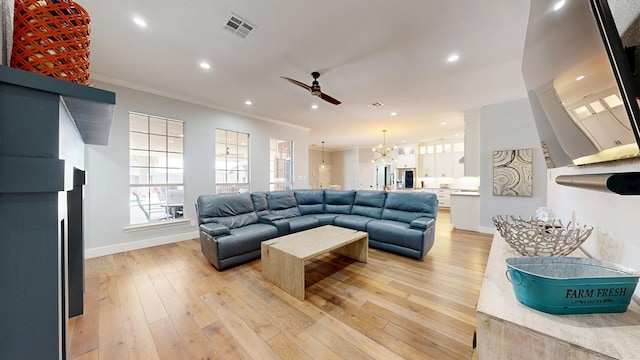 living area featuring light wood-type flooring, baseboards, visible vents, and crown molding