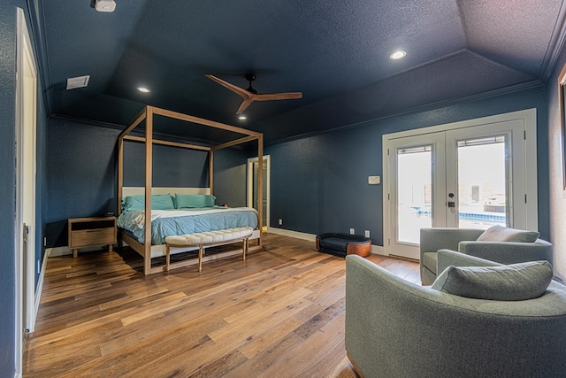 bedroom featuring access to exterior, french doors, lofted ceiling, a textured ceiling, and wood finished floors