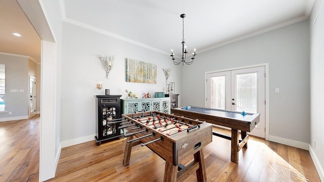 rec room with baseboards, light wood-style flooring, ornamental molding, an inviting chandelier, and french doors