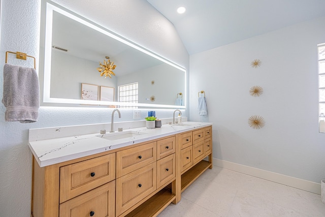 bathroom with lofted ceiling, double vanity, a sink, and baseboards