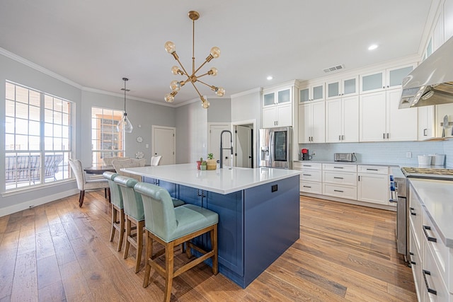 kitchen with ornamental molding, extractor fan, stainless steel appliances, light wood-type flooring, and backsplash