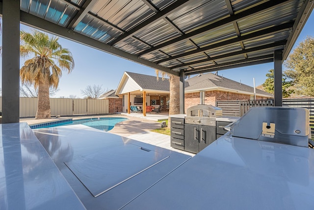 view of pool featuring an outdoor kitchen, a fenced in pool, a patio, a fenced backyard, and a grill