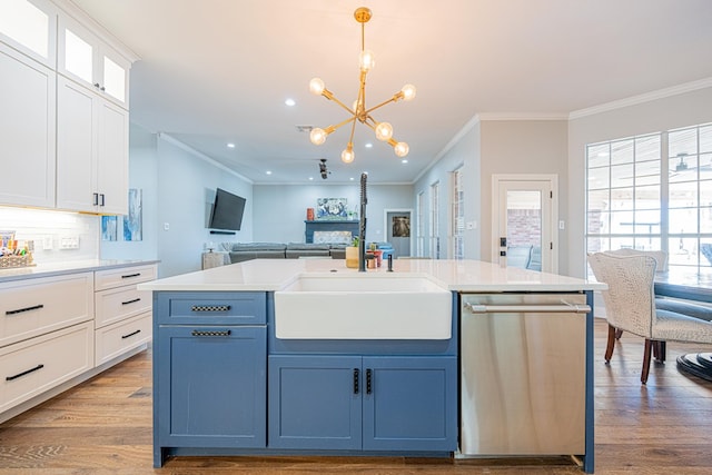 kitchen with white cabinets, open floor plan, wood finished floors, stainless steel dishwasher, and a sink