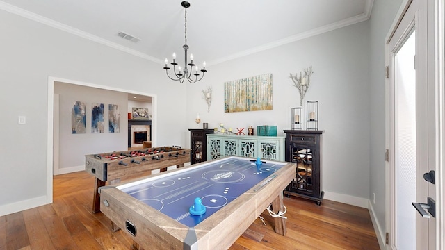 recreation room featuring baseboards, visible vents, hardwood / wood-style floors, and ornamental molding