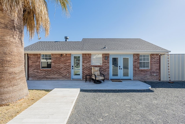 exterior space with a shingled roof, french doors, and brick siding