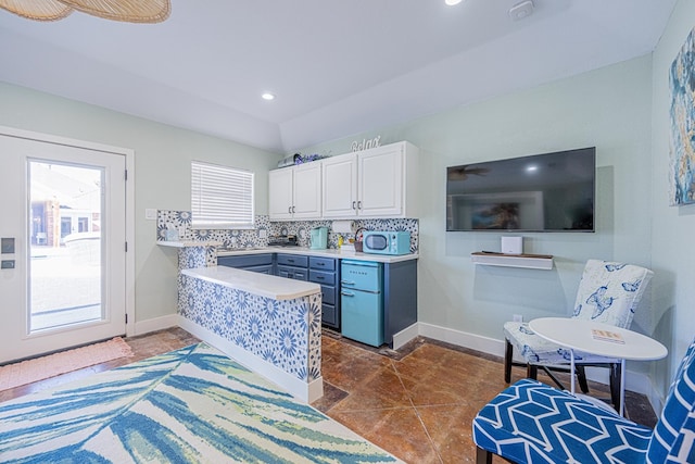 kitchen featuring baseboards, white cabinetry, light countertops, and backsplash