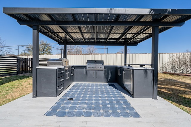 view of patio / terrace featuring exterior kitchen, a fenced backyard, and a grill