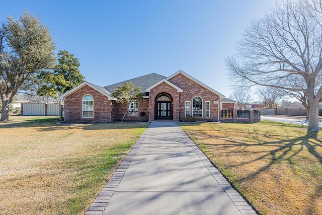 view of front of property featuring brick siding, fence, and a front lawn