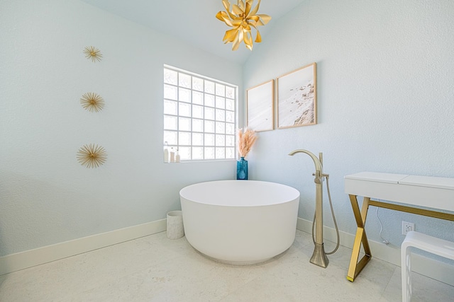 bathroom featuring a freestanding tub and baseboards