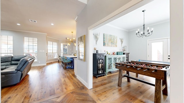 rec room with baseboards, ornamental molding, visible vents, and an inviting chandelier