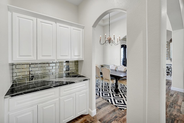 7704 W County Rd 52 Unit A, Midland, TX 79707 - kitchen with a chandelier, tasteful backsplash, dark stone counters, white cabinets, and dark wood-style flooring