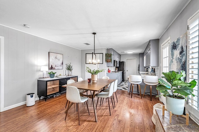 dining space with an inviting chandelier, baseboards, visible vents, and wood finished floors